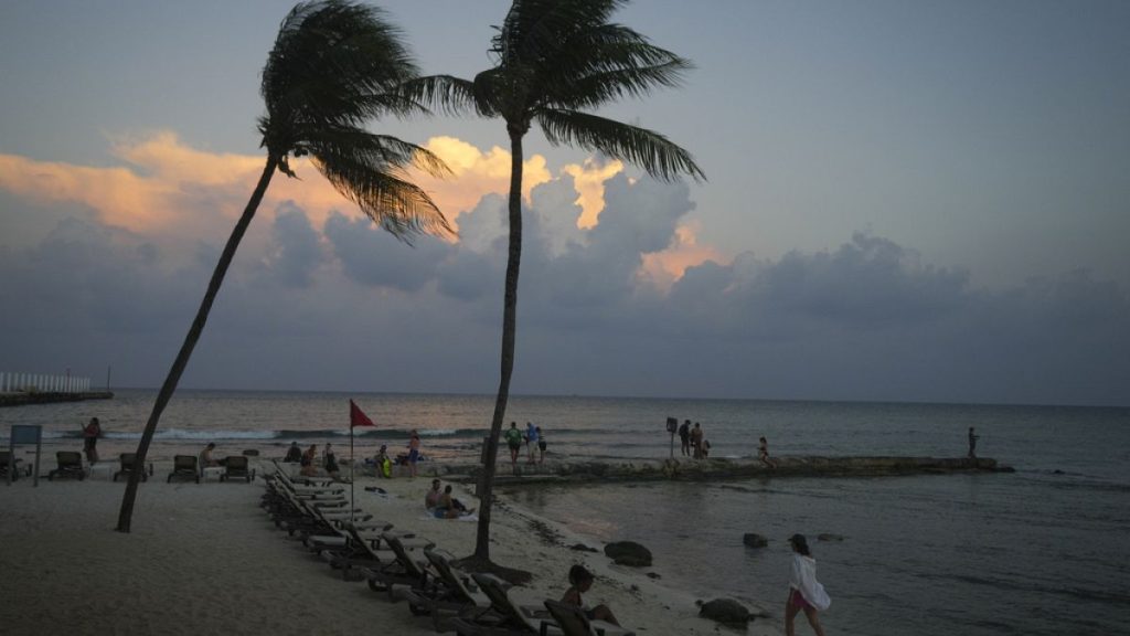 People lounge on the beach as the sun sets ahead of Hurricane Beryl