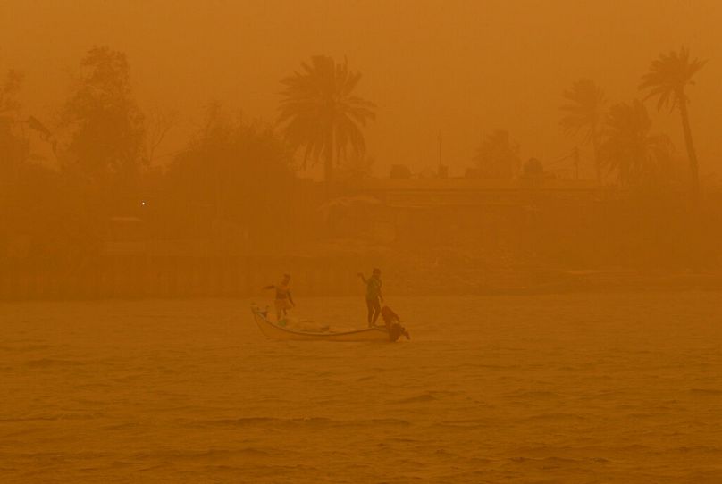 Des pêcheurs naviguent sur la voie navigable de Chatt al-Arab pendant une tempête de sable à Bassora, en Irak