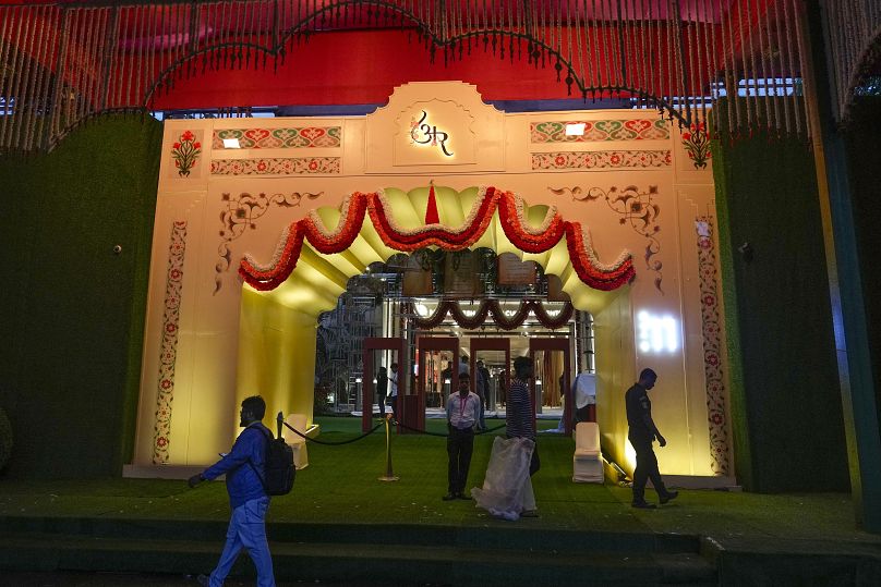 Les gens passent devant la salle décorée de lumières avant le mariage du fils du milliardaire Mukesh Ambani, Anant Ambani, avec Radhika Merchant au Jio World Convention Centre à Mumbai