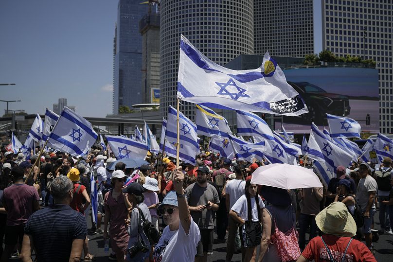 Des manifestants brandissent des drapeaux israéliens lors d'une manifestation à Tel-Aviv marquant les neuf mois du début de la guerre à Gaza, le 7 juillet 2024