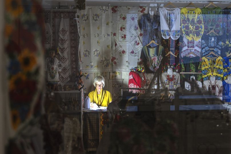 Un vendeur éclaire avec une lampe de poche lors d'une panne de courant dans un centre commercial souterrain du centre de Kiev, en Ukraine, le mercredi 19 juin 2024 (AP Photo/Efrem Lukatsky)