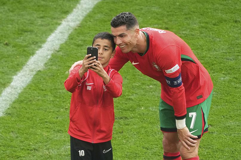 Un jeune envahisseur de terrain prend un selfie avec le Portugais Cristiano Ronaldo lors d'un match de groupe du tournoi de football Euro 2024 en Allemagne.