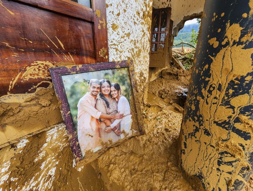 Une photographie encadrée est partiellement recouverte de boue dans une maison endommagée après que des glissements de terrain ont frappé des villages vallonnés du district de Wayanad, dans l'État du Kerala, en Inde, le mardi 30 juillet 2024.