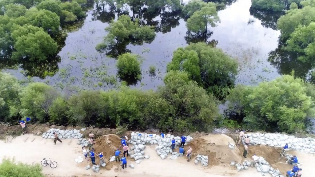 In this image made from video provided by Russian Emergency Situations Ministry press service, volunteers build dams to prevent a flood.