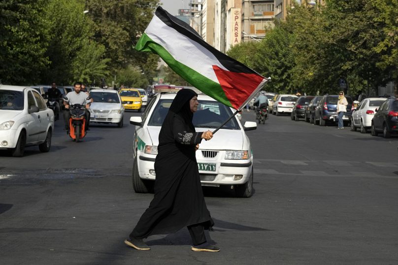 Une femme iranienne porte un drapeau palestinien pour condamner le meurtre du chef du Hamas Ismail Haniyeh, sur la place Felestin (Palestine) à Téhéran, en Iran, le mercredi 31 juillet 2024. 