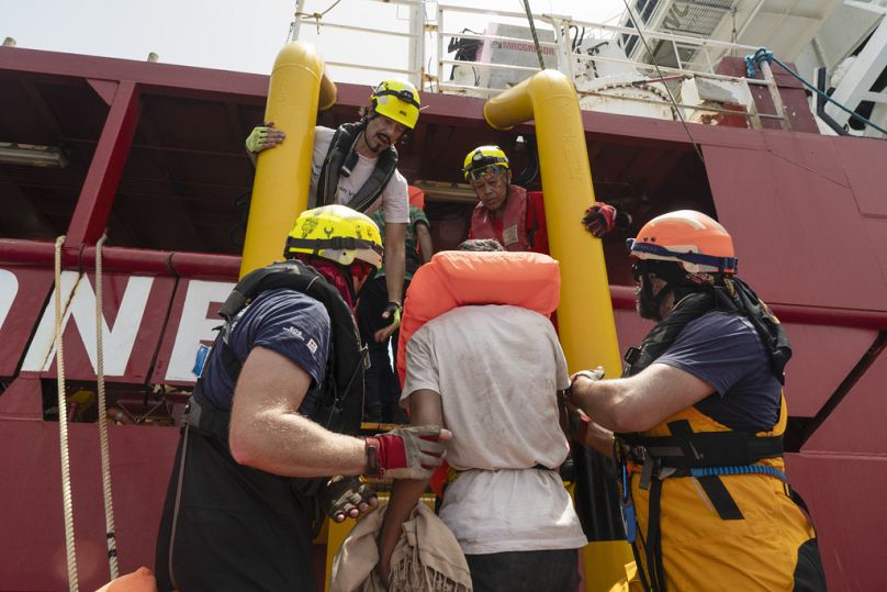 Les sauveteurs bénévoles de SOS Méditerranée aident à transférer les passagers d'un bateau de migrants en bois sur leur propre navire de sauvetage en mer Méditerranée, en juillet 2024.