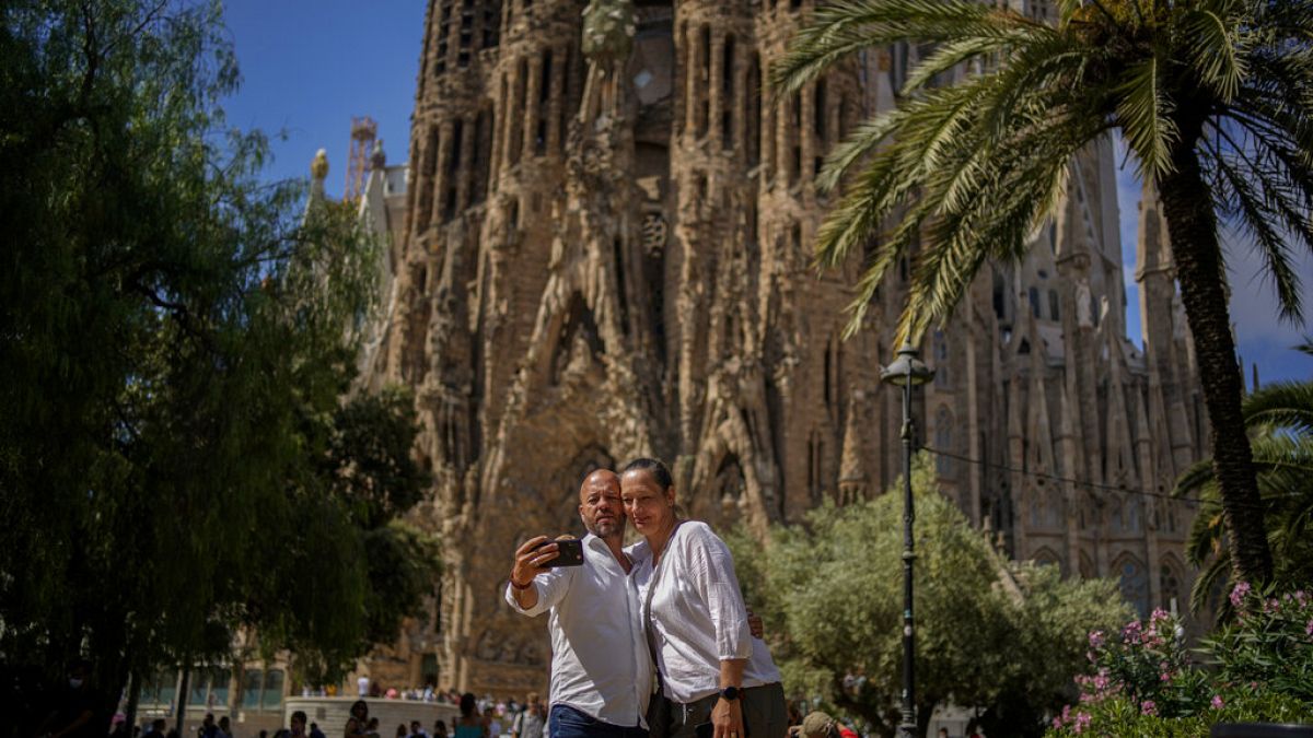 A couple pose for a picture in front of Sagrada Familia Basilica designed by architect Antoni Gaudi in Barcelona, Spain, Friday, July 9, 2021