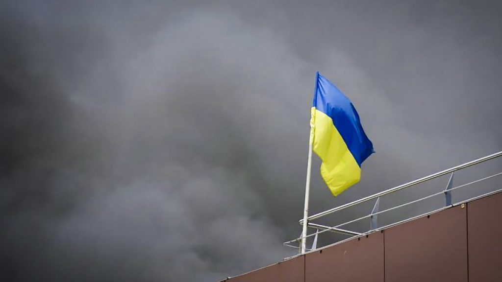 Ukrainian flag waves as smoke rises after Russia