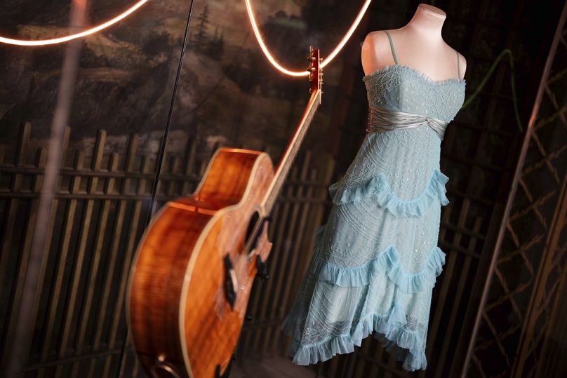 Une guitare et un costume de scène des tournées de concerts précédentes sont exposés à l'exposition « Taylor Swift Songbook Trail Exhibition » au Victoria & Albert Museum.