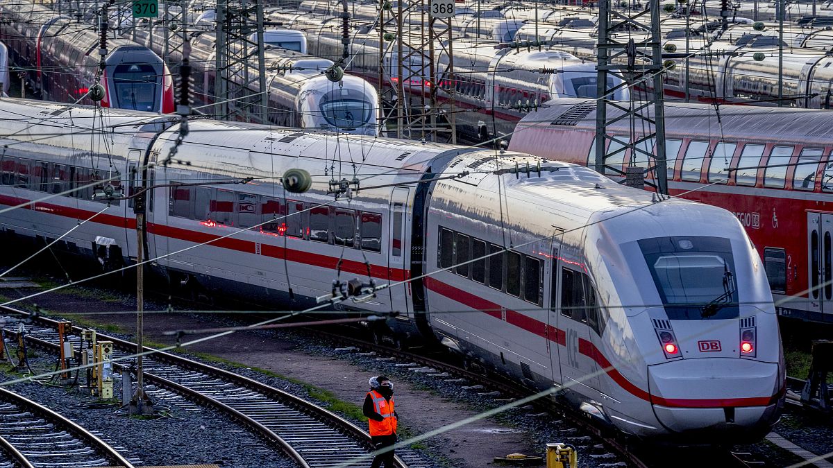 A Deutsche Bahn employee walks past ICE trains that are parked near the central train station in Frankfurt, Germany, Monday, March 27, 2023.