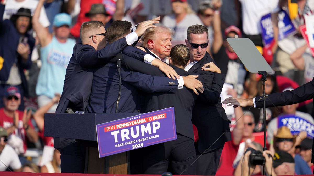 Former President Donald Trump is helped off the stage at a campaign event in Butler, July 13, 2024