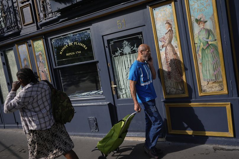 Des gens passent devant un restaurant décoré d'œuvres d'art, avant les Jeux olympiques d'été de 2024 à Paris, en juillet 2024