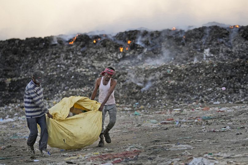 Usmaan Shekh, à droite, porte, avec de l'aide, un sac de matériaux recyclables collectés dans une décharge pendant une vague de chaleur à la périphérie de Jammu, en Inde