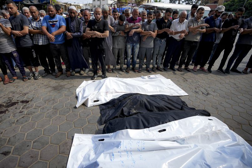 Des Palestiniens prient à côté des corps de leurs proches tués dans le bombardement israélien de la bande de Gaza, dans un hôpital de Deir al-Balah, dimanche 21 juillet 2024.