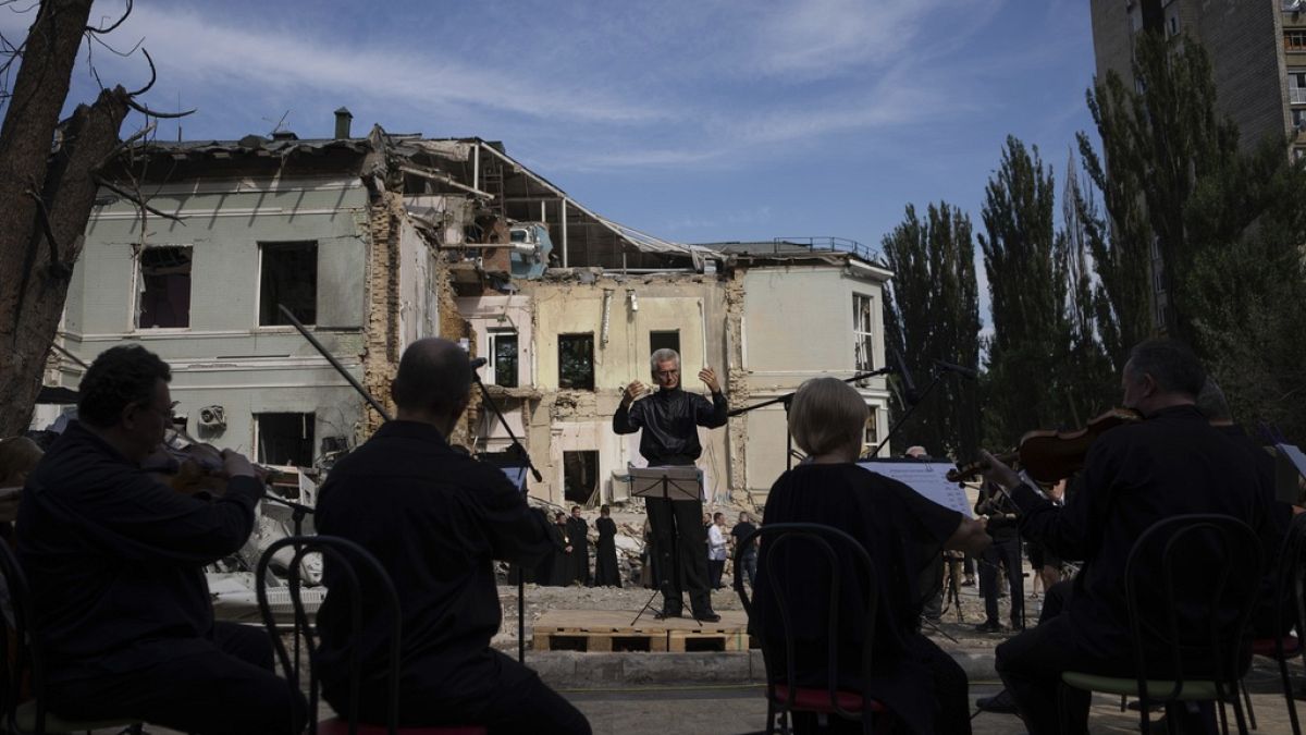 The conductor German Makarenko leads the orchestra, which is playing on the site of the Russian missile attack on the children