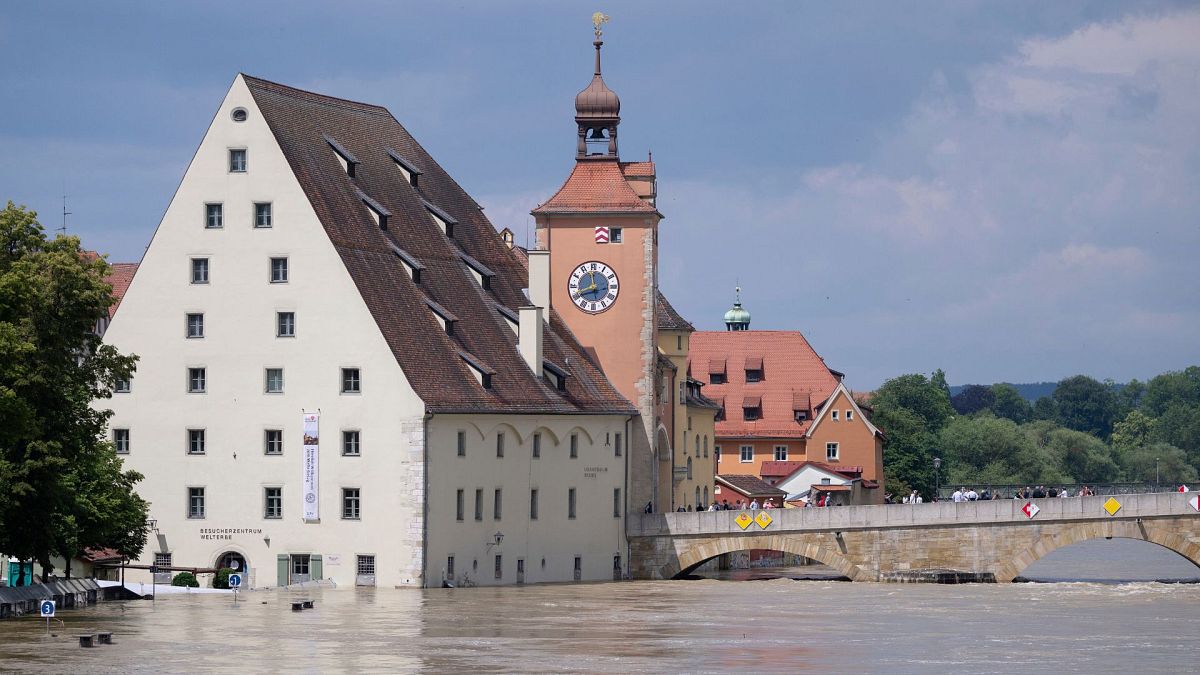 People stand on the Stone Bridge in the old town and watch the floods on the Danube, in Regensburg, Germany, 5 June 2024.