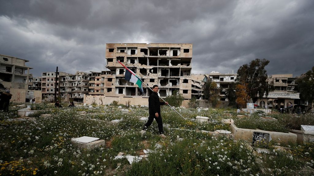A man carries a Palestinian flag in a the Yarmouk refugee camp in Damascus, Syria.