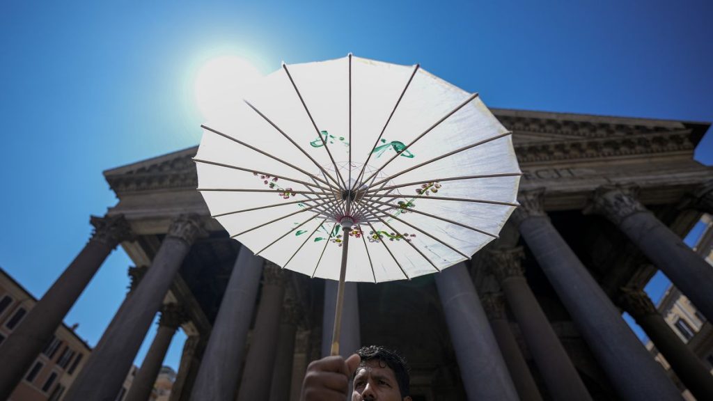 A man shields from the sun with a paper umbrella in front of Rome