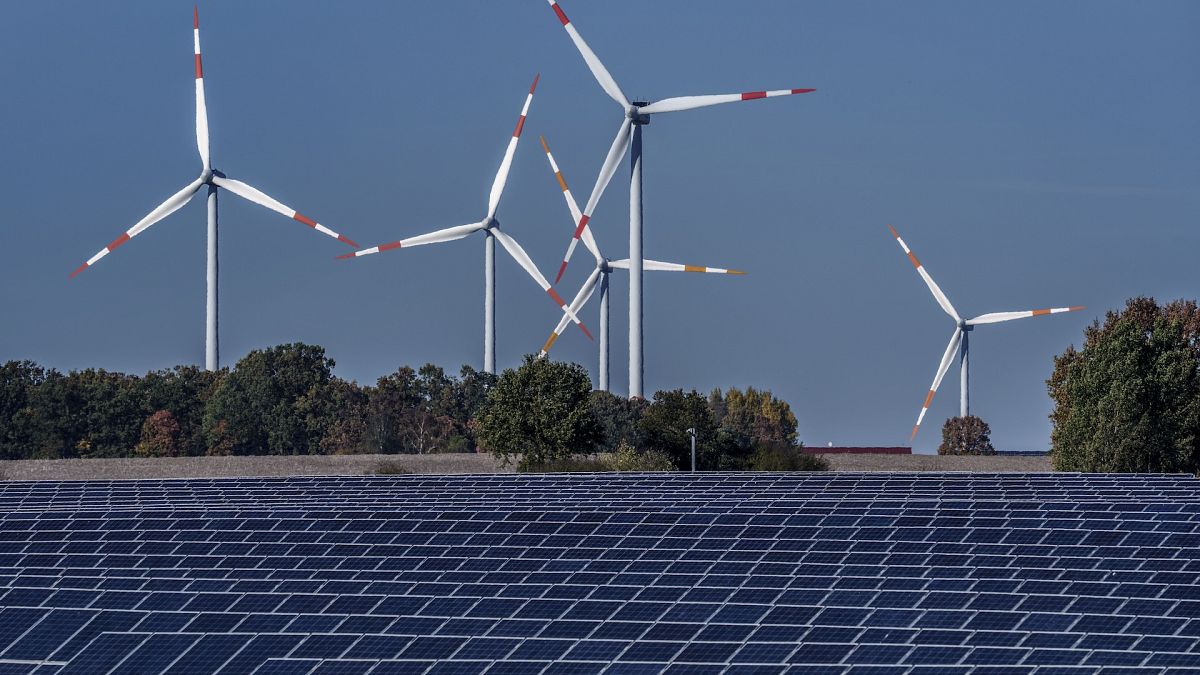 Wind turbines turn behind a solar farm in Rapshagen, Germany