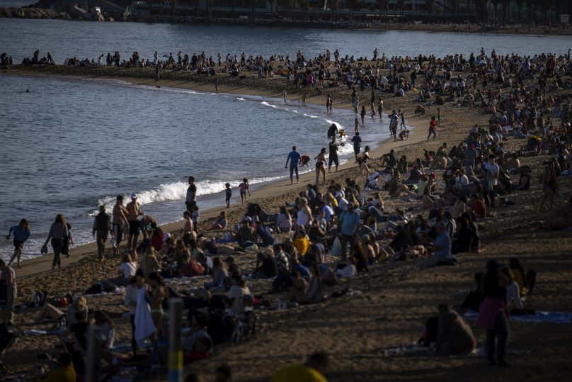   Les gens prennent le soleil sur une plage de Barcelone, en Espagne, le dimanche 12 mars 2023.