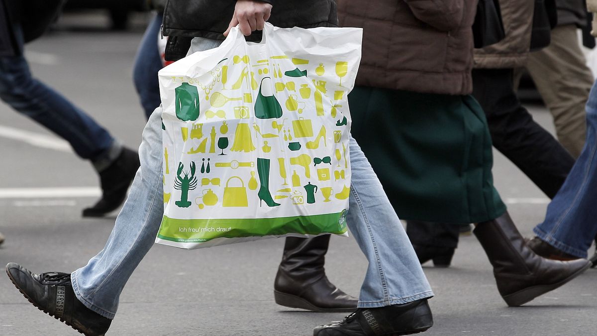 A man with a shopping bag crosses a street in Berlin, Germany