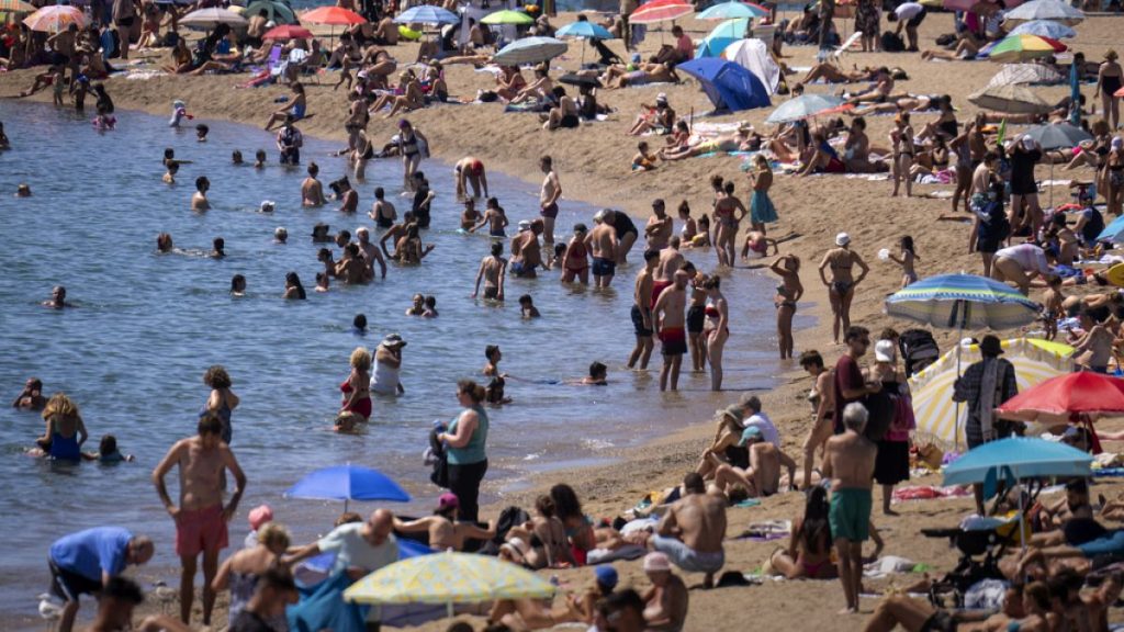 Bathers cool off in the water while others sunbathe on a Barcelona beach, Spain, Wednesday, July 24, 2024.