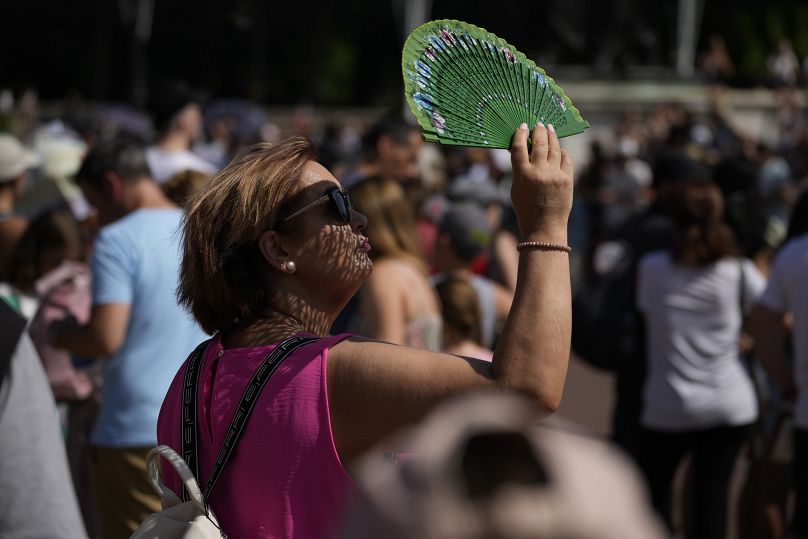 Une femme utilise un ventilateur pour se protéger du soleil pendant une vague de chaleur à Londres, en juillet 2022.