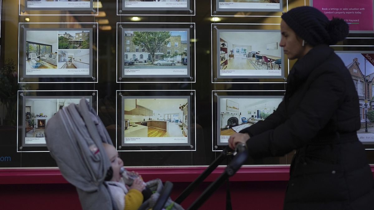 A woman walks past an estate agent in London.