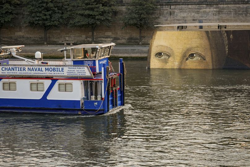 Un navire passe devant des reproductions d'œuvres d'art décorant les rives de la Seine lors des Jeux olympiques d'été de 2024, mardi