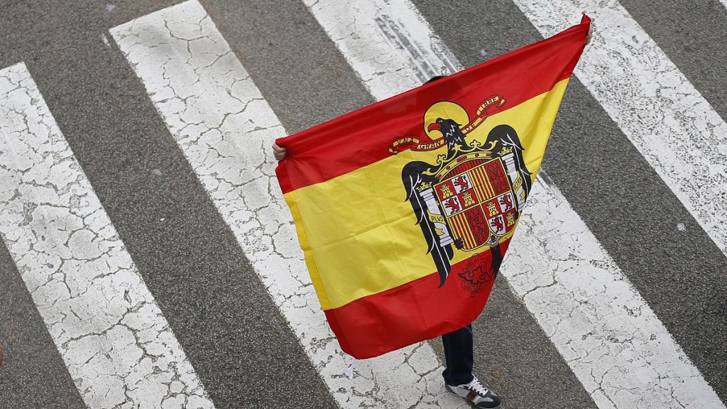 A man holds a pre-constitutional flag during a demonstration for the unity of Spain as they celebrate Spain