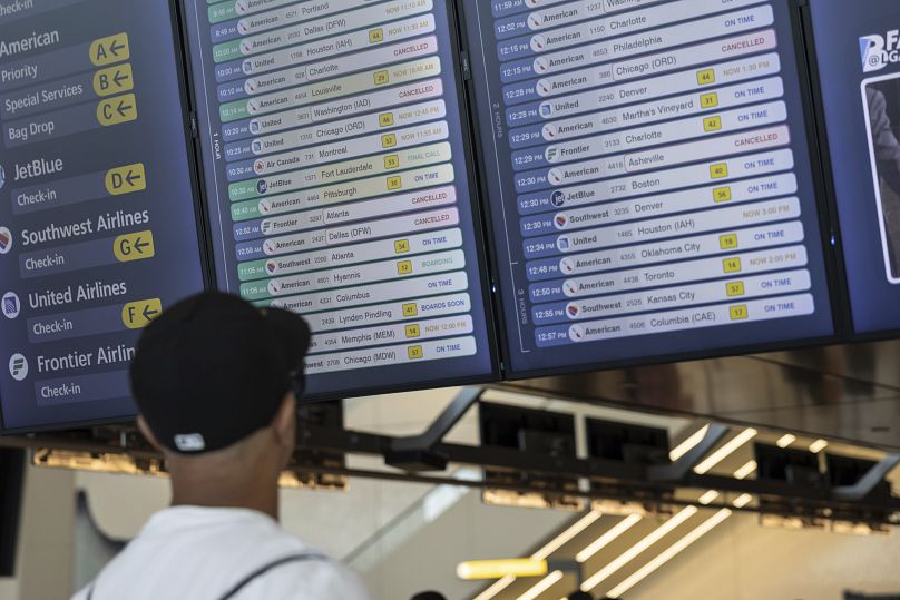 Une personne vérifie les horaires des vols sur l'écran à l'étage des départs de l'aéroport de LaGuardia à New York, le 19 juillet 2024