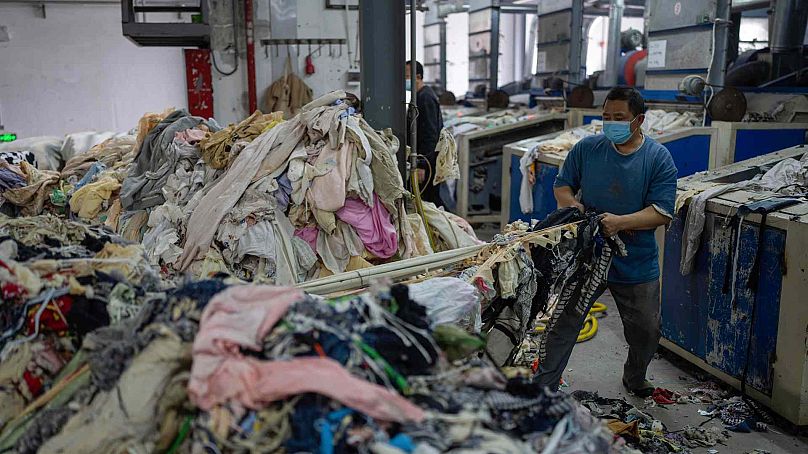 Un ouvrier alimente une machine à déchiqueter avec des textiles mis au rebut à la Wenzhou Tiancheng Textile Company, l'une des plus grandes usines de recyclage de coton de Chine, à Wenzhou, dans l'est de la Chine.