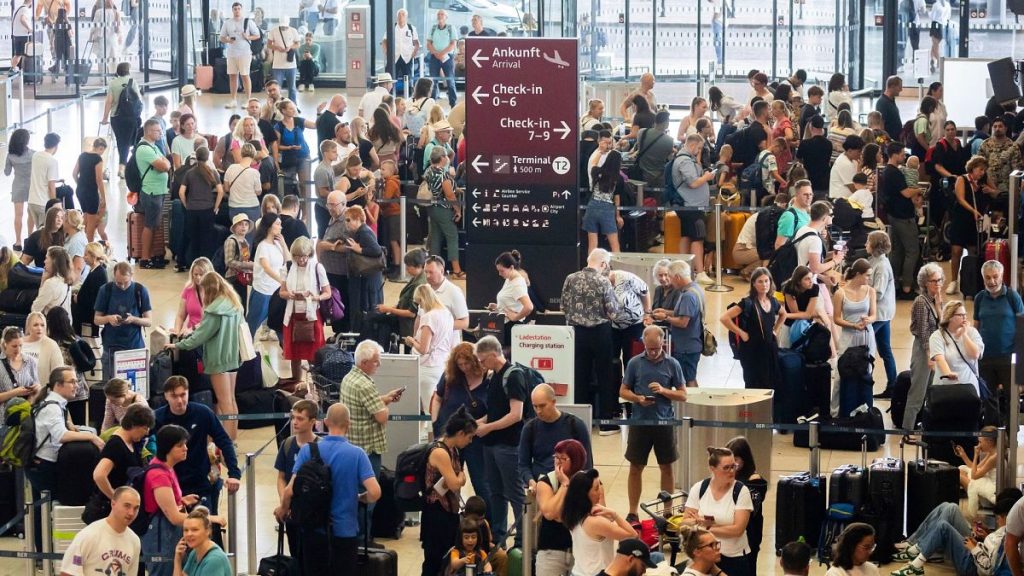 Passengers wait at Berlin Brandenburg Airport, Germany, after a widespread technology outage disrupted flights on 19 July 2024.