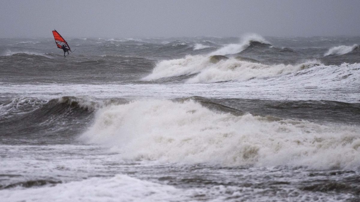 A wind surfer rides on waves at the Baltic Sea near Kuehlungsborn, Germany, Friday, Oct. 20, 2023.