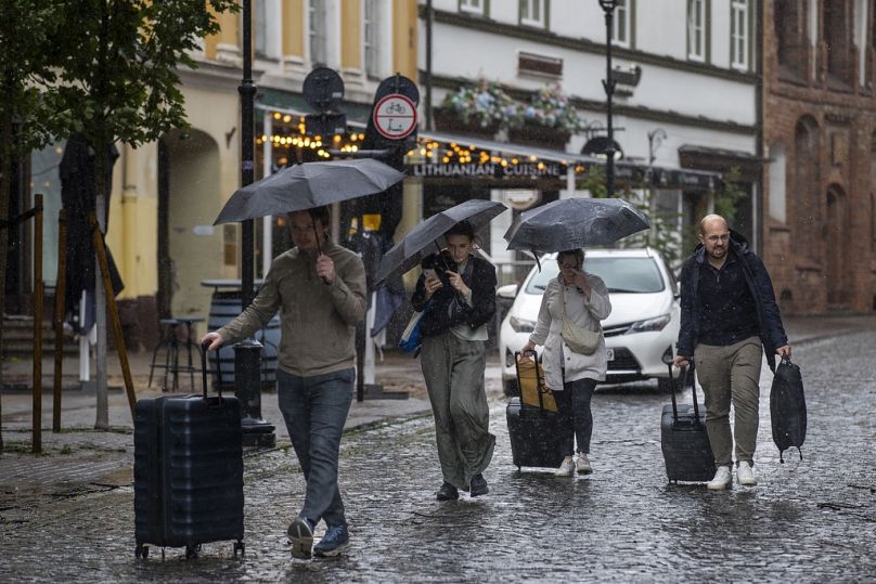 Les gens s'abritent de la pluie sous des parapluies un jour de pluie, à Vilnius, en Lituanie, le lundi 29 juillet 2024.