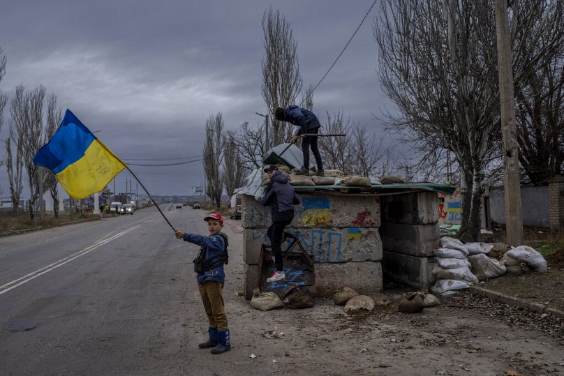 Des enfants ukrainiens jouent à un poste de contrôle abandonné à Kherson, le 23 novembre 2022