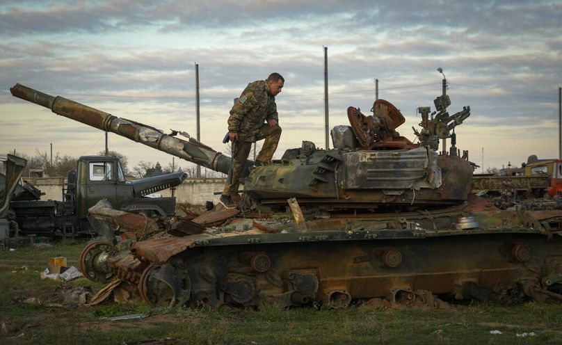 Un soldat ukrainien inspecte un char russe endommagé dans le village récemment repris de Chornobaivka près de Kherson, le 15 novembre 2022