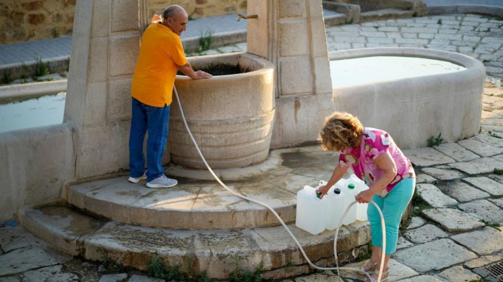 Antonino Contino, left, and his wife Antonella Croce fill jerry cans with water for daily use at Agrigento