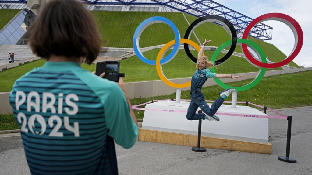 Olympic volunteer Manuella Mallam has her photo taken with the Olympic rings outside Bercy Arena ahead of the 2024 Summer Olympics, Tuesday, July 23, 2024, in Paris, France.