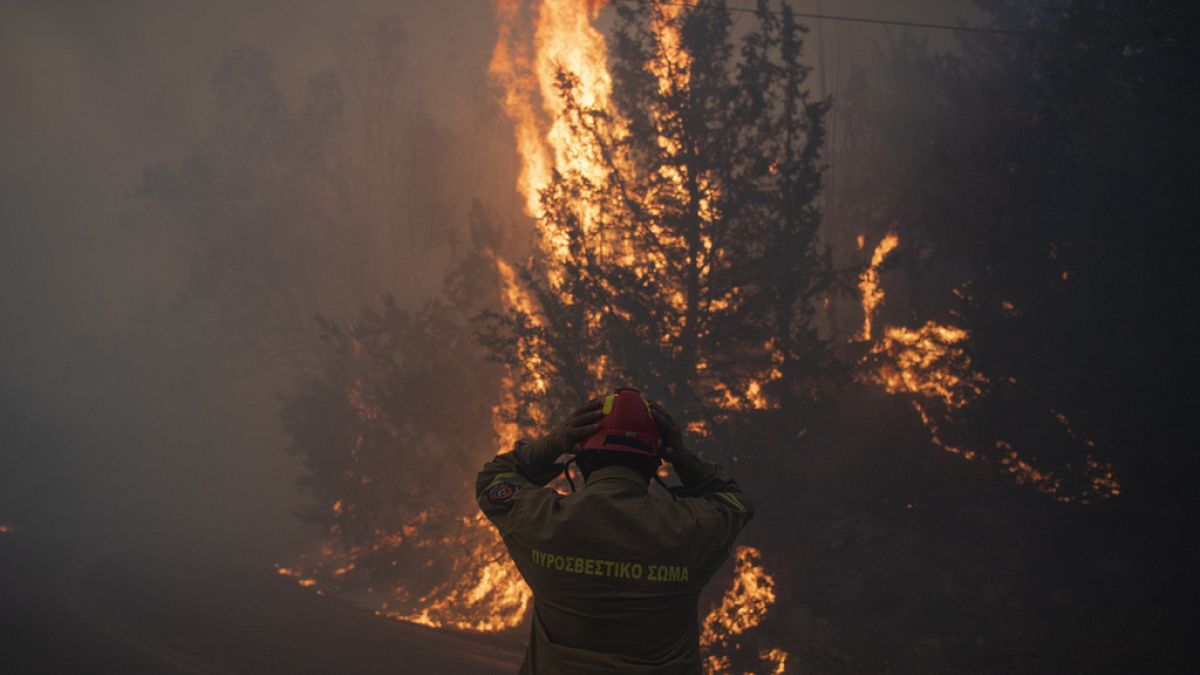 A firefighter adjusts his helmet in north of Athens, Greece, Sunday, Aug. 11, 2024.