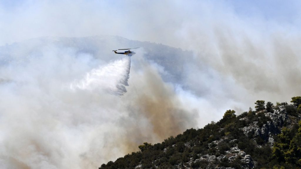 A helicopter drops water over a fire in Nea Makri, east of Athens, Monday, Aug. 12, 2024.