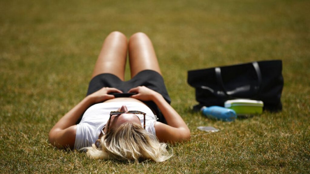 A woman sunbathes in hot weather in St James