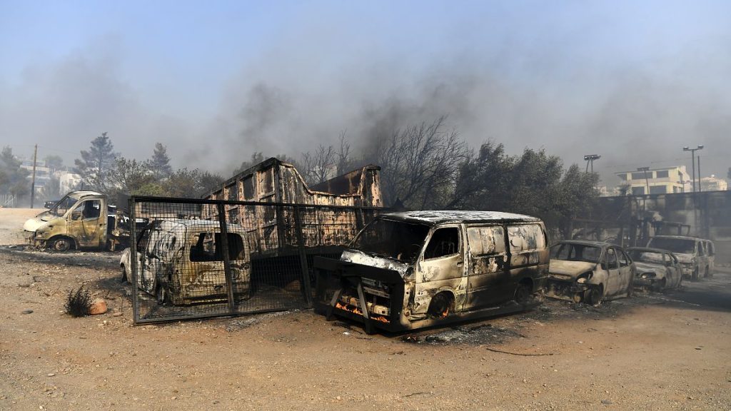 Flames burn a vehicle at a business during a fire in northern Athens, Monday, Aug. 12, 2024,