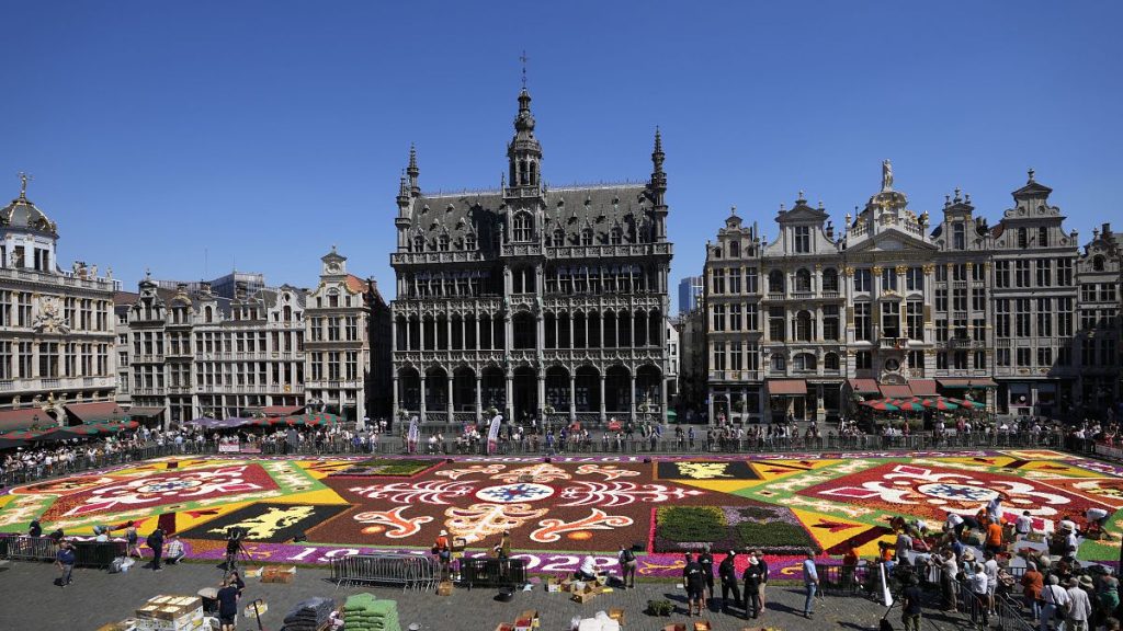 The public looks at a giant flower carpet created by volunteers on the historical Grand Place in Brussels, Friday, Aug. 12, 2022.