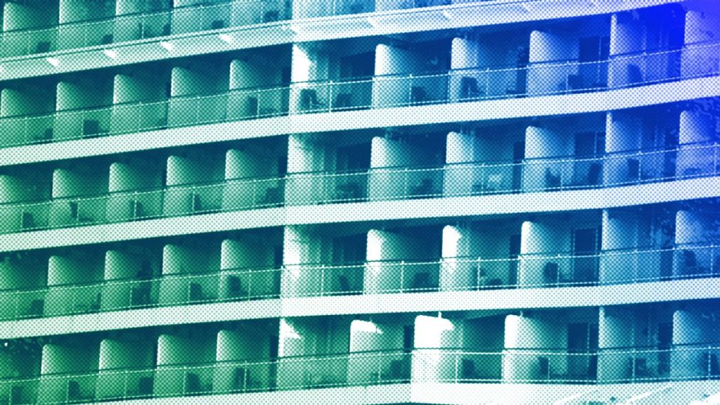 A woman stands on the balcony of a cruise ship which is docked at Athens