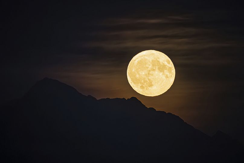 Une soi-disant super lune bleue s'élève au-dessus de la "Dent d'Oche" montagne vue depuis Allaman, Suisse, lundi 19 août 2024.