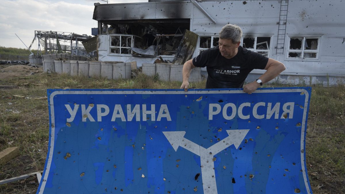 Ukrainian historian Yuri Savchuk, head of the Kyiv-based Ukrainian WWII history museum, carries a road sign in Sudzha, Kursk region, Russia, Friday, Aug. 16, 2024. This image