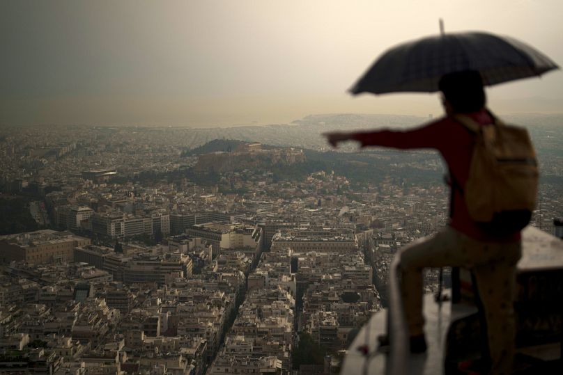 Un touriste tient un parapluie pendant une averse soudaine sur la colline de Lycabette, à Athènes, en Grèce.