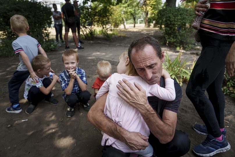 Un père serre sa fille dans ses bras, ses autres enfants à proximité, alors qu'ils attendent d'être évacués à Pokrovsk, dans la région de Donetsk, en Ukraine, le vendredi 23 août 2024.