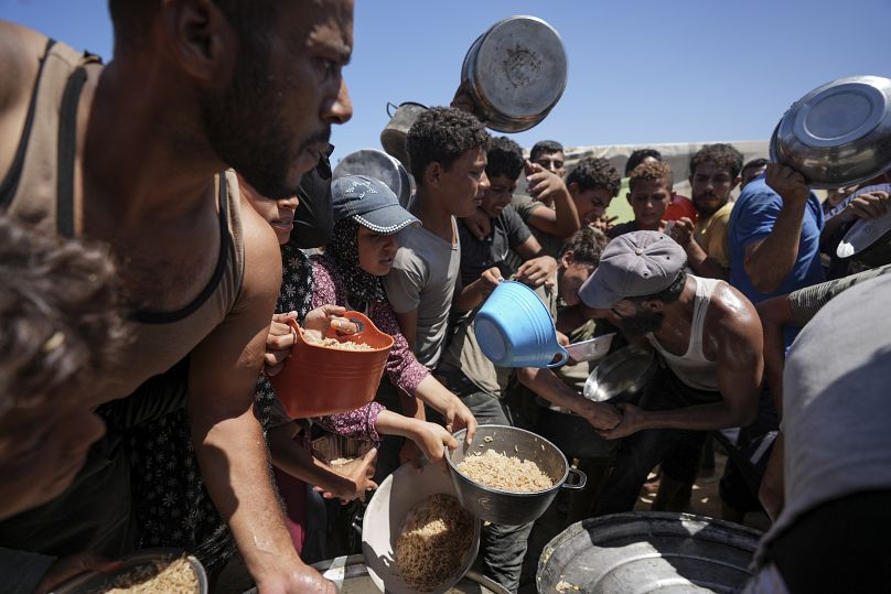 Des Palestiniens déplacés se rassemblent pour une distribution de nourriture à Deir al Balah, dans le centre de la bande de Gaza, le vendredi 23 août 2024.